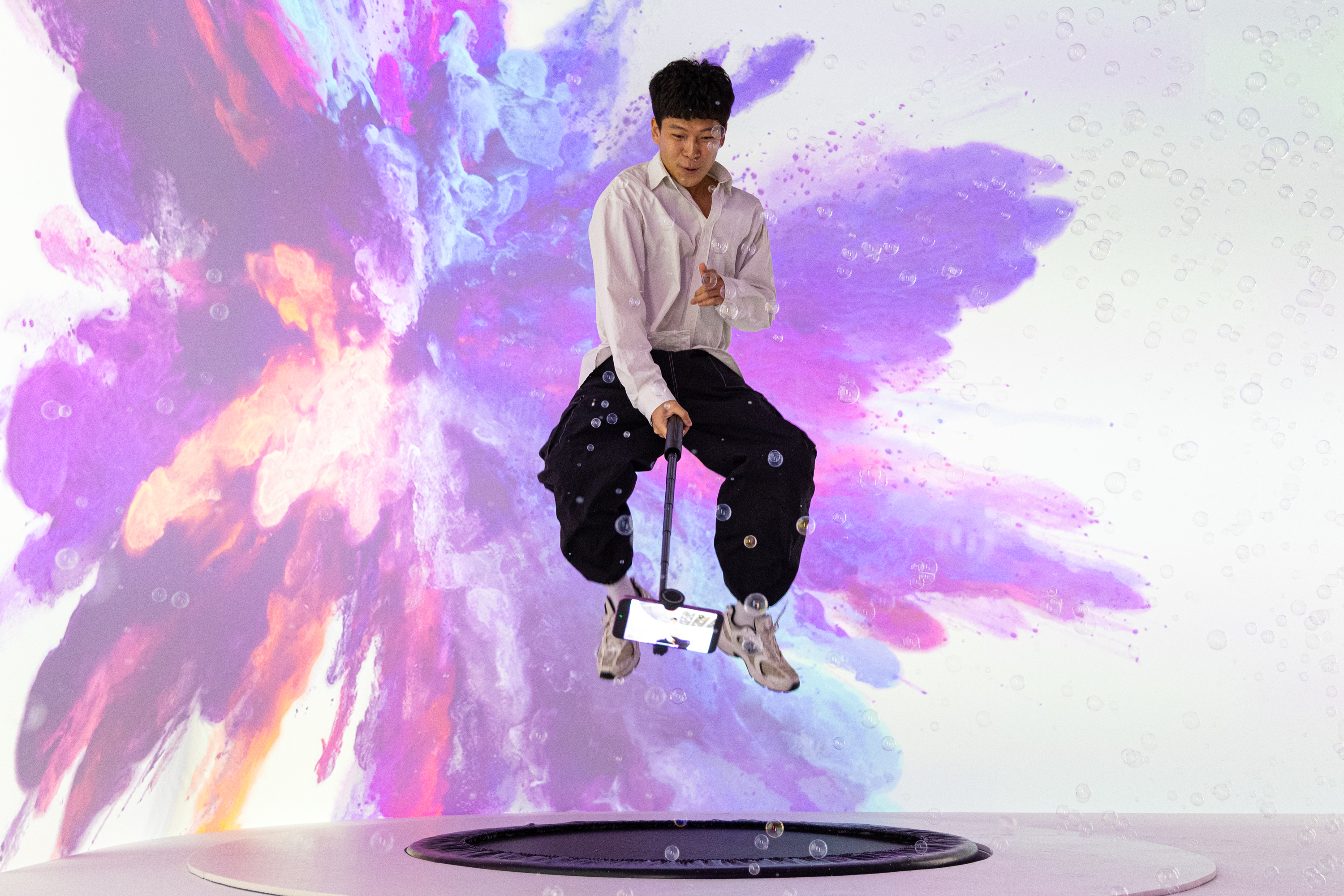 A creator mid-bounce on the trampoline, filming with a phone on a gimbal