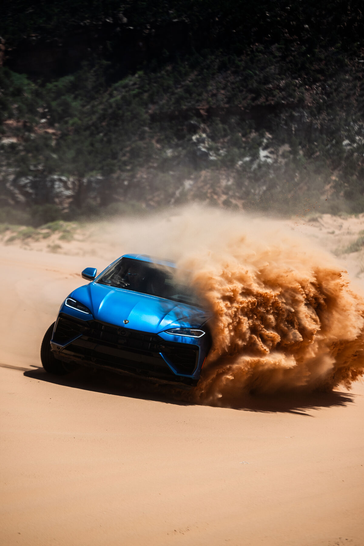 A Urus SE throwing sand on the dune driving section