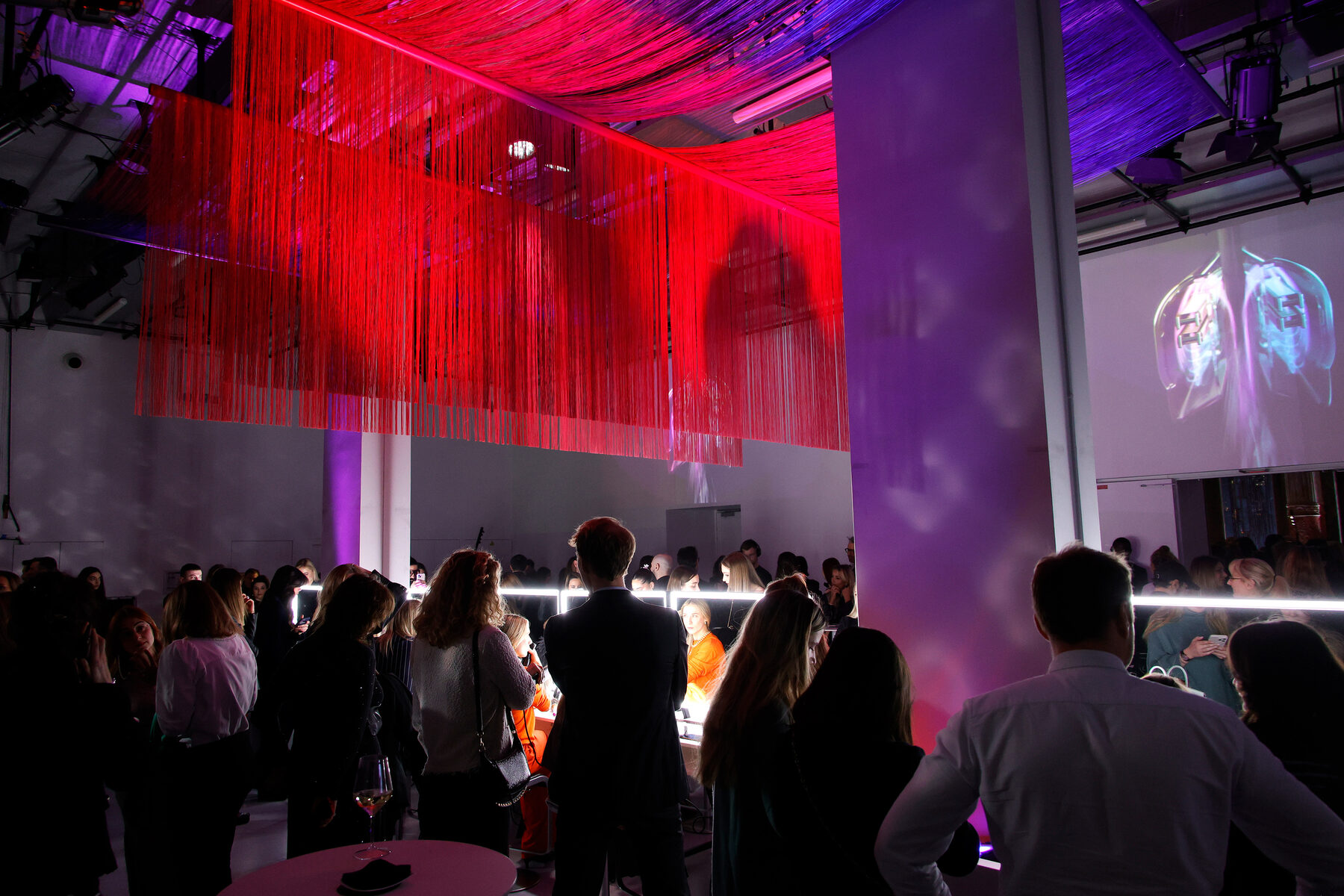 The Dyson Airstrait launch space in Paris, guests beneath a red fringed ceiling installation