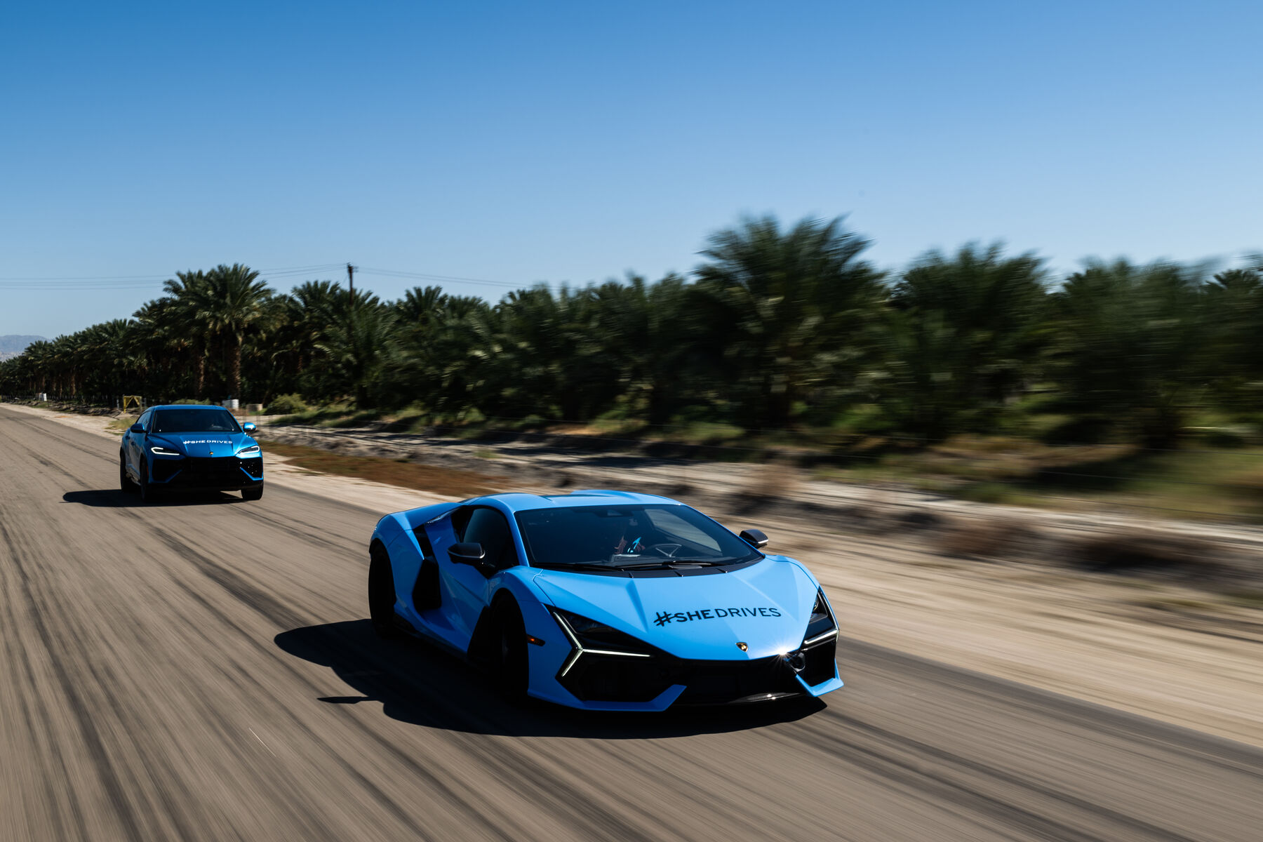 Two supercars on the scenic drive route past desert palms