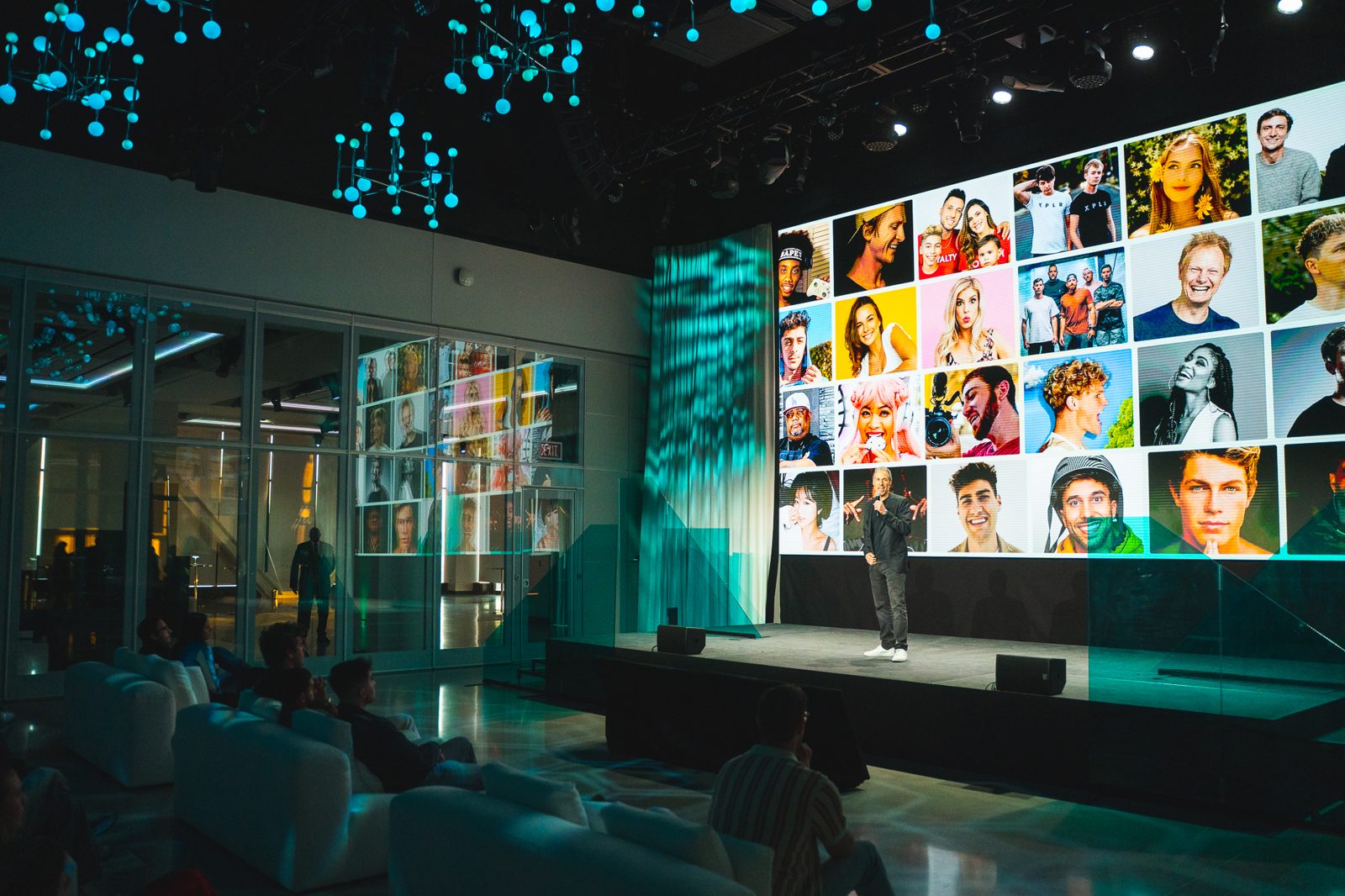 A presenter on the Spotter Showcase stage in front of a creator portrait wall